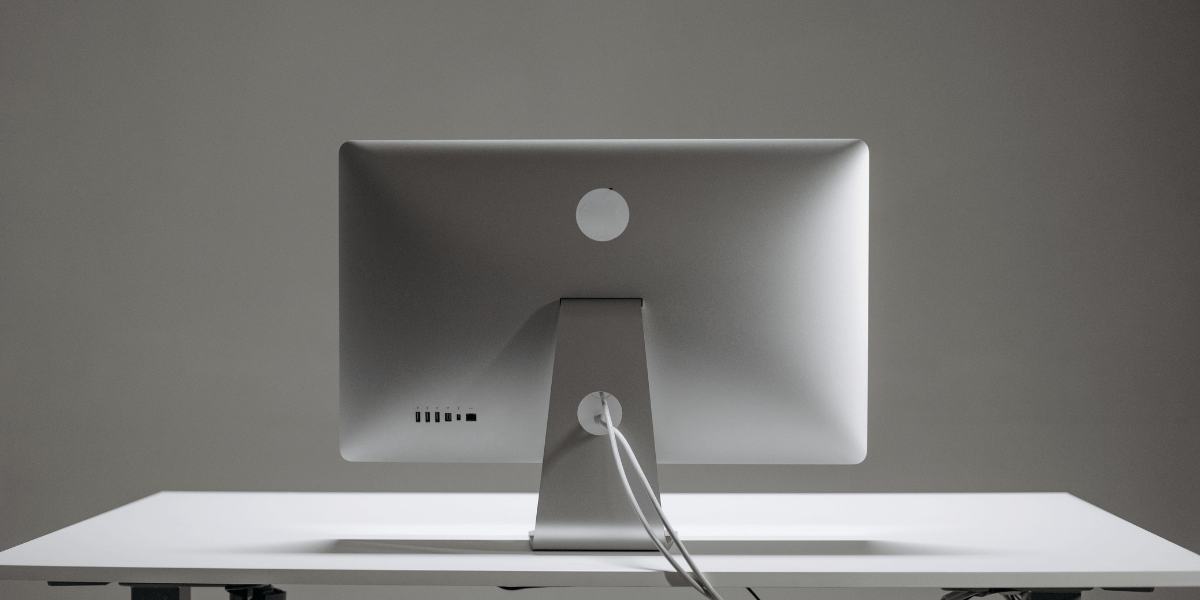 Back view of a sleek silver computer monitor on a minimalist white desk