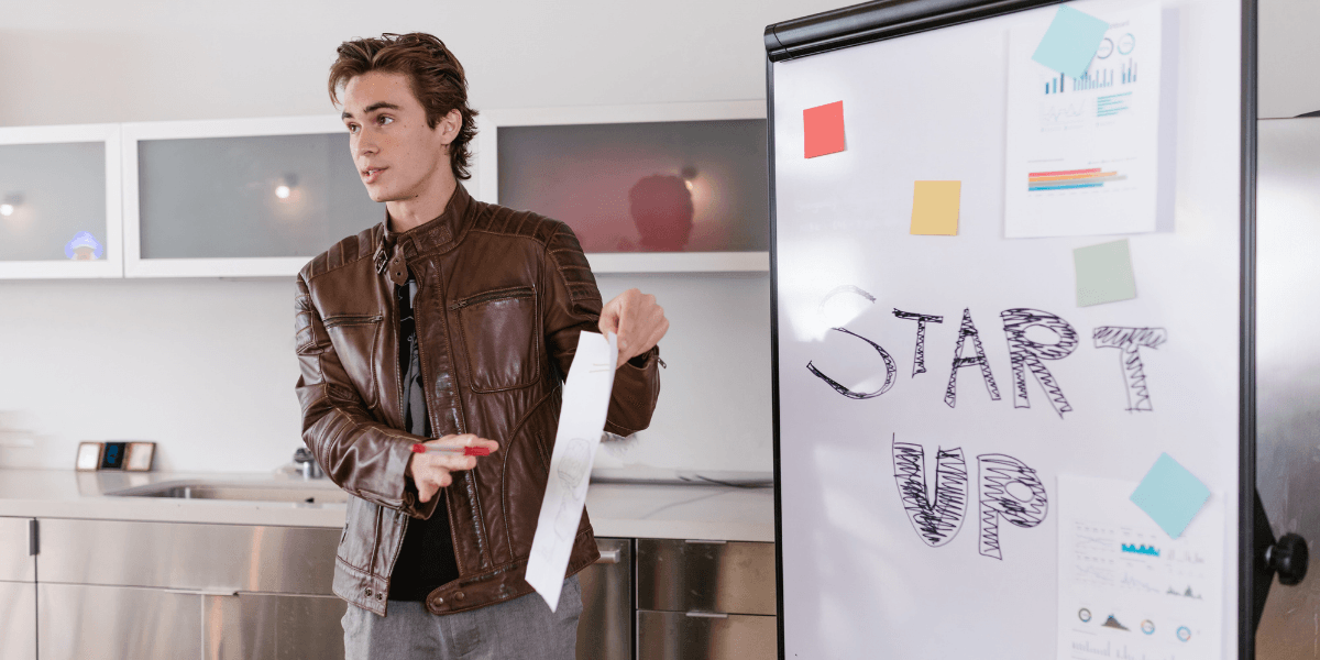 Young man presenting by a whiteboard with "START UP" written on it