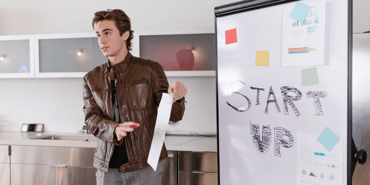 Young man presenting by a whiteboard with "START UP" written on it