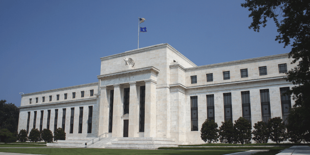Federal Reserve building with flag, featuring a marble facade and classical architecture