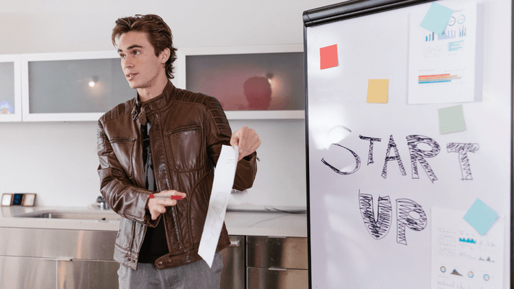 Young man presenting by a whiteboard with "START UP" written on it