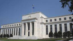 Federal Reserve building with flag, featuring a marble facade and classical architecture