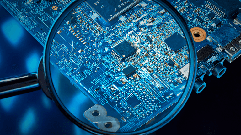 Close-up of a circuit board viewed through a magnifying glass against a blue background
