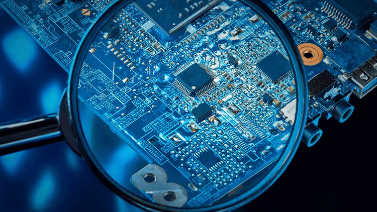 Close-up of a circuit board viewed through a magnifying glass against a blue background
