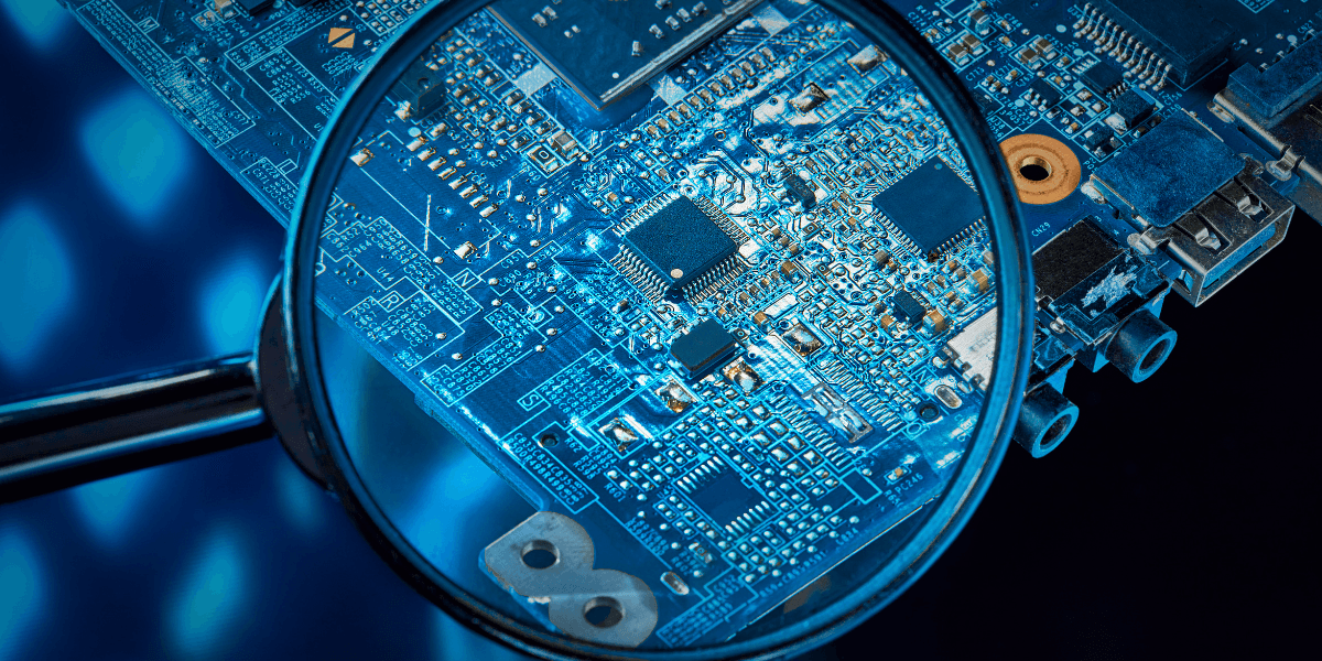 Close-up of a circuit board viewed through a magnifying glass against a blue background