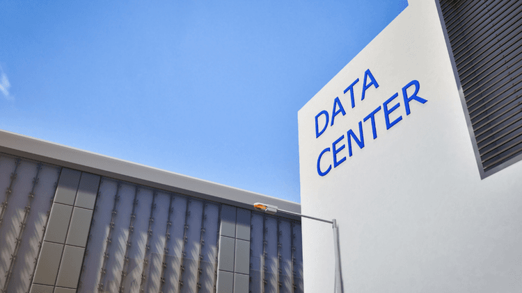 Modern data center building with a clear blue sky above and signage.