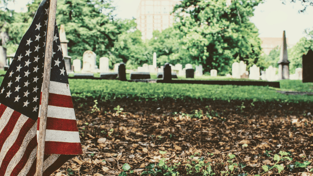 American flag placed in a cemetery among gravestones and fallen leaves