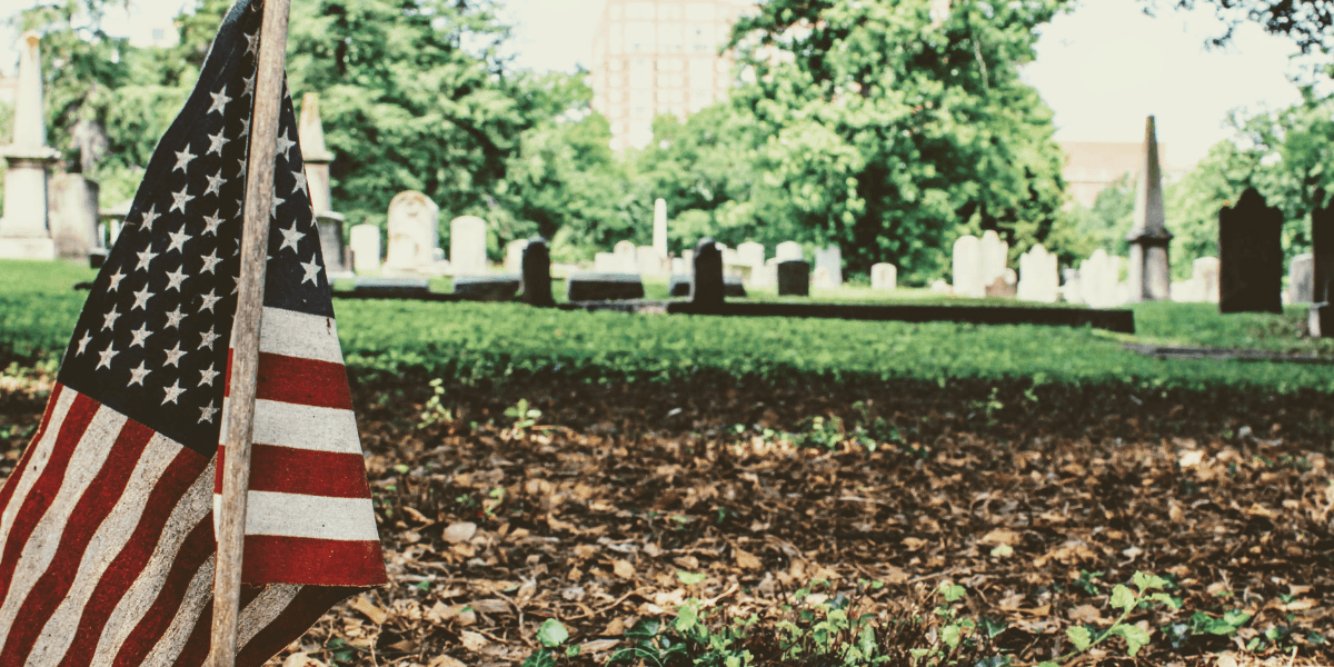 American flag placed in a cemetery among gravestones and fallen leaves