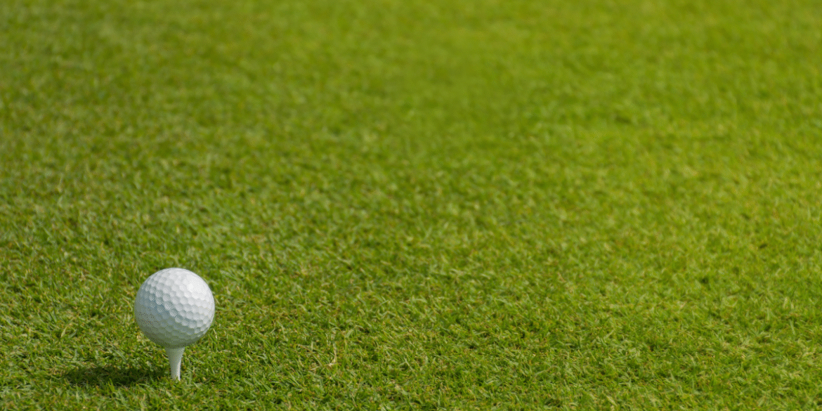 Golf ball on a tee positioned on a well-maintained golf course fairway.